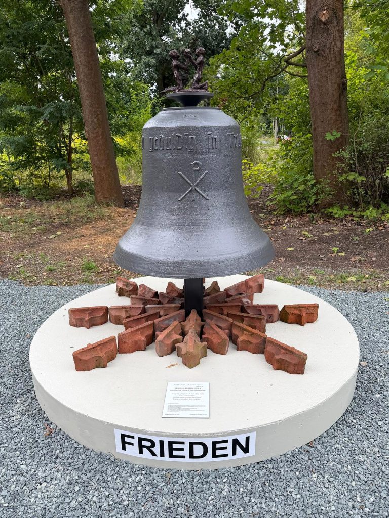 Friedensglocke mit Figurengruppe auf einem runden Sockel mit der Aufschrift FRIEDEN