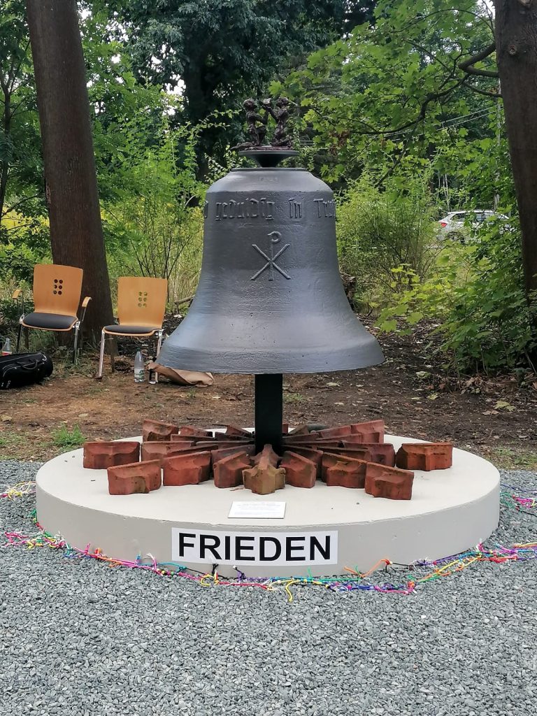 Fertig gestaltete Friedensglocke mit Figurengruppe und der Aufschrift FRIEDEN am Sockel